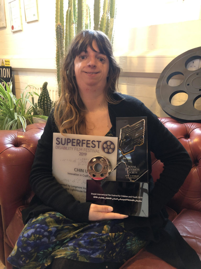 Chin Up's director, JoAnne Salmon, displaying some of the awards Chin Up received in 2019